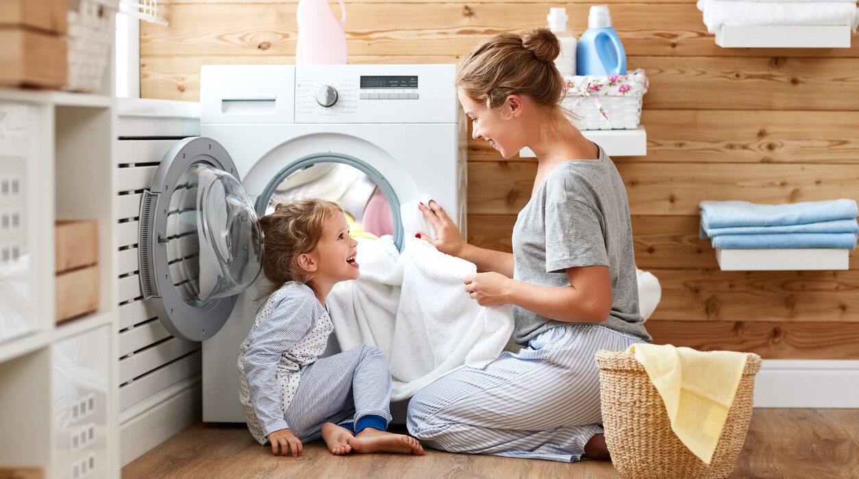 Çamaşır makinesine kıyafet koyan kadın ve kızı
